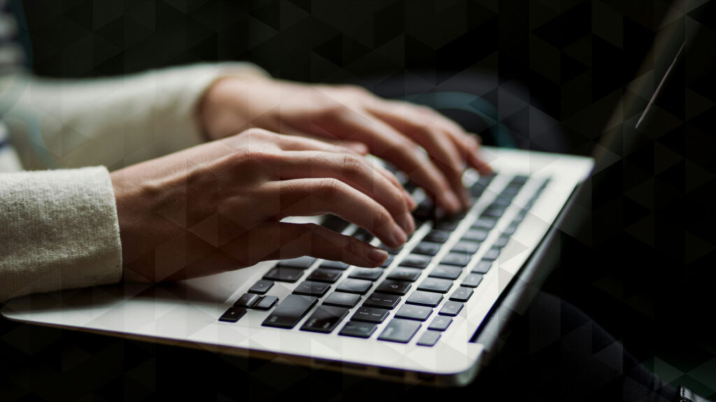 Hands typing on a laptop keyboard