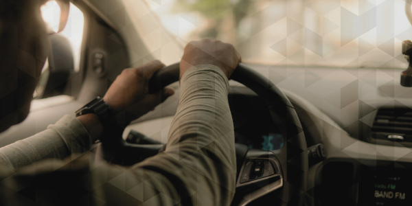 Man driving a car. Image is showing the steering wheel.